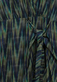 Flerfärgad tyg med vertikala gröna, blå och svarta ränder. Texturerad yta med en knutdetalj i mitten som skapar ett lager-på-lager utseende.