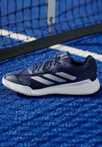 Granatowe buty sportowe z teksturowaną cholewką, białymi akcentami i podeszwą Cloudfoam, umiejscowione na niebieskiej syntetycznej powierzchni w pobliżu siatki.