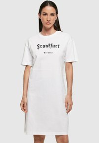 Fehér pamut t-shirt ruha rövid ujjal, amelyen fekete szöveg olvasható: "Frankfurt Németország" vastag betűkkel. Egyszerű, egyenes vonalú fazon.