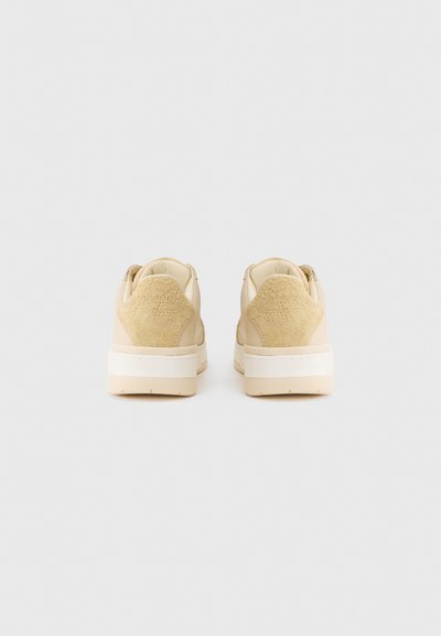 Μπεζ αθλητικά παπούτσια με λείο δερμάτινο σώμα και υφασμένο σουέντ τακούνι, με λευκή λαστιχένια σόλα και μινιμαλιστικό σχέδιο.