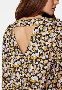 Bluse mit floralem Muster, schwarzer Hintergrund mit gelben, lavendelfarbenen und weißen Blattmustern; Keyhole-Rückendetail und gerafften Ärmeln.
