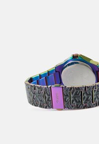 Mehrfarbige metallische Armbanduhr mit einem schwarzen gemusterten Band, ausgestattet mit einer lila Schließe und einem runden metallischen Gehäuse.