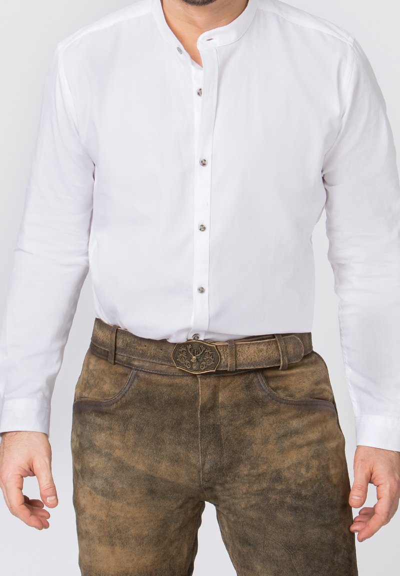 Chemise blanche à manches longues avec patte de boutonnage, associée à un pantalon en cuir marron à finition texturée et boucle de ceinture décorative.