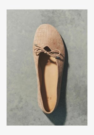 Bézs színű velúr balettcipő dombornyomott hálómintával és elöl masnival, felülről, szürke felületen bemutatva.