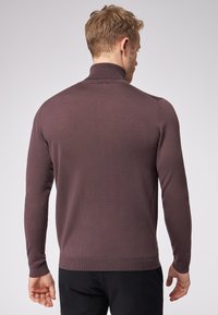Brauner, gestrickter Pullover mit hohem Kragen und langen Ärmeln. Besitzt eine taillierte Passform und gerippte Struktur. Rückansicht gezeigt.