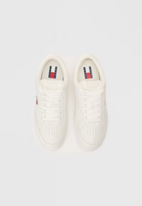 Tenisi albi cu vârf perforat, șireturi plate, formă rotundă a vârfului, material din piele texturată și logo contrastant albastru și roșu pe lateral.
