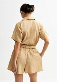 Robe chemise en lin beige à manches courtes, taille ceinturée et large short.Texture lisse et design minimaliste, vue de dos.