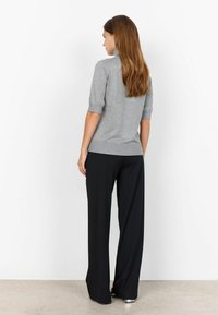 Top tricotat gri cu mâneci scurte, asortat cu pantaloni largi negri. Materialul pare moale, având un design ajustat pe umeri.