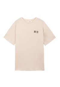 Μπεζ κοντομάνικο μπλουζάκι με μαύρους Ιαπωνικούς χαρακτήρες "Τόκιο" που είναι τυπωμένοι στο αριστερό στήθος, στρογγυλή λαιμόκοψη και κανονική εφαρμογή.