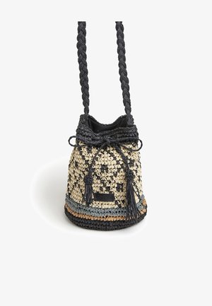 Tkany worek na ramię w naturalnych i czarnych odcieniach, z plecionymi uchwytami, akcentami w postaci frędzli oraz zapięciem na ściągacz. Teksturowana powierzchnia.