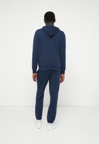 Navy blue hooded sweatshirt and matching sweatpants made of cotton blend fabric, featuring ribbed cuffs and relaxed fit.
