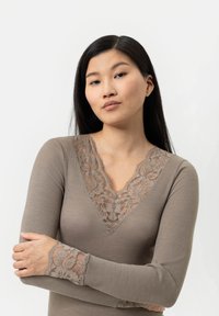 Brown ribbed long-sleeve top featuring a V-neck with floral lace detailing at the neckline and cuffs. Smooth fabric texture.