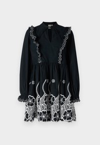 Μαύρο φόρεμα με μακριά μανίκια, ρυακιές στον γιακά και κεντημένα λευκά λουλούδια στο τελείωμα. Αυχένας με κλειδαρότρυπα και λεπτομέρεια με συγκεντρωμένη μέση.