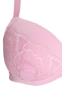 Light pink bra featuring a smooth fabric with floral lace overlay detailing on the cup, adjustable straps, and seamless edges.