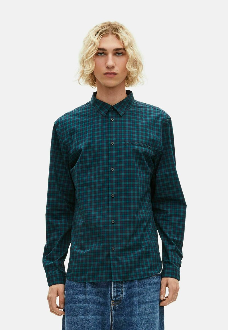 Camicia a maniche lunghe con bottoni in un motivo a quadri blu e verde scuro, dotata di colletto, taschino sul petto e bottoni neri. Tessuto in cotone.