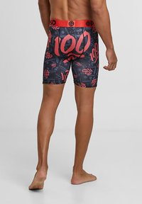 Shorts de boxeur noirs avec un motif comportant un grand "100" rouge et des accents. Taille élastique avec une marque, longueur jusqu'au milieu de la cuisse.