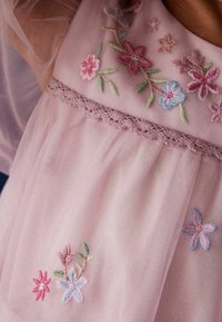 Helles rosa Tüllkleid mit floralen Stickereien in Pastellfarben, zartem Spitzenbesatz an der Taille und transparenten Puffärmeln.