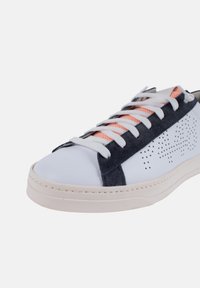 Baskets de sport avec une tige en cuir blanc, des accents en daim bleu marine et un design perforé. Elles présentent des lacets blancs et des détails en mesh orange. Semelle en caoutchouc.