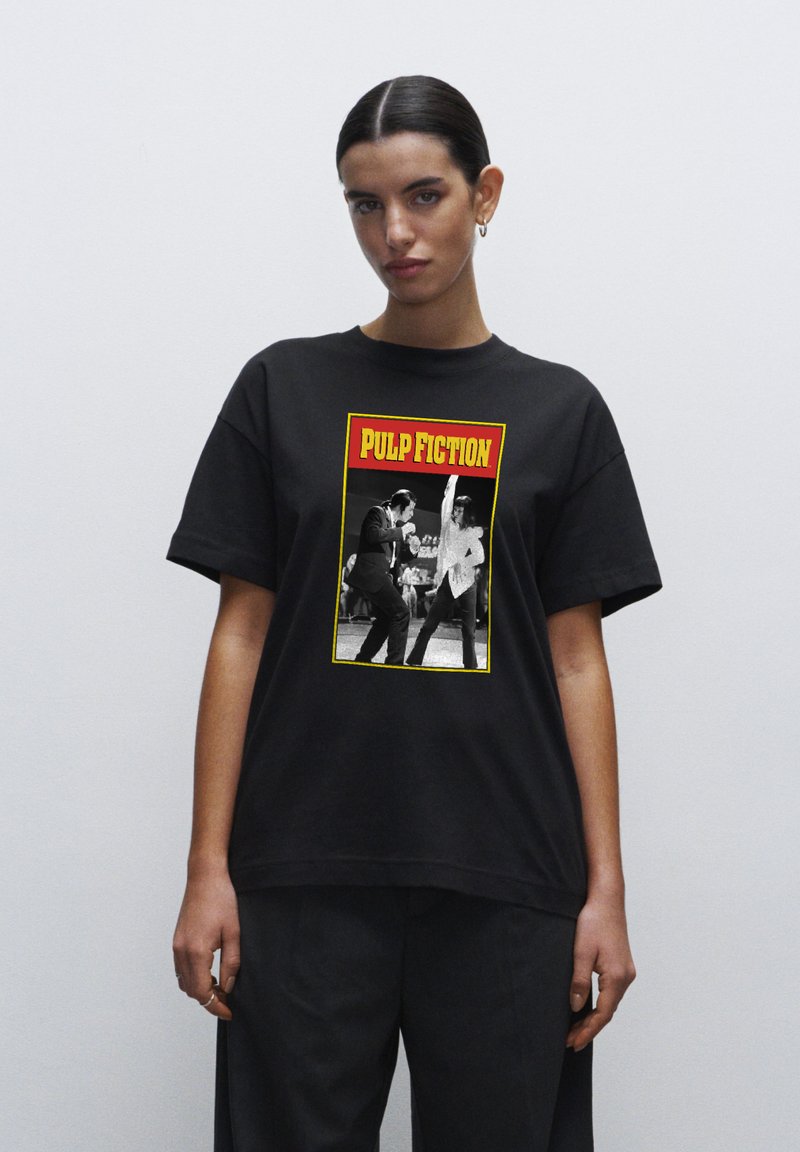Černé bavlněné tričko s grafickým potiskem dvou postav z "Pulp Fiction" v černé a bílé barvě, s designem ohraničeným červenou a žlutou barvou.