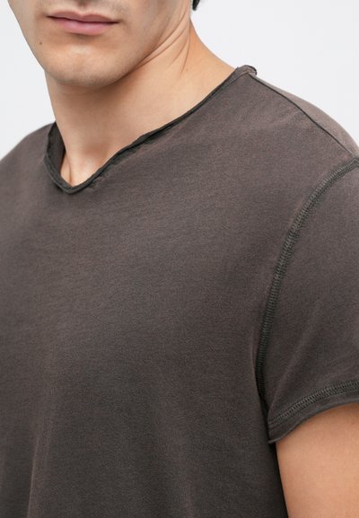T-shirt curto de manga curta em cinza escuro com uma textura suave, um decote em V ligeiramente desgastado e costuras visíveis ao longo das bordas.