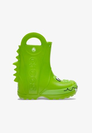 Green rubber rain boot with a textured surface, smiley face, and dorsal ridges. Features a handle for easy wearing and a gripped sole.
