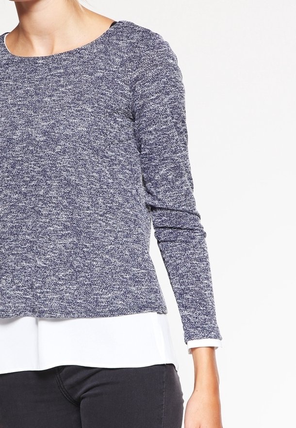 Långärmad tröja i marinblått stickat med en melerad textur, rund halsringning och en kontrasterande vit undertröja synlig vid fållen.
