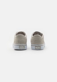 Grey suede sneakers with a low profile, featuring a white rubber sole and "66/99" embossed on the heel. Vans logo on the back.