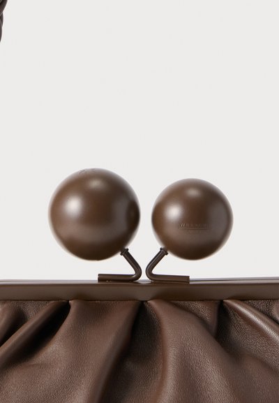 Sac à main en cuir marron avec une texture froncée et des poignées supérieures rondes. Le matériel remarquable comprend deux accents sphériques à finition mate.