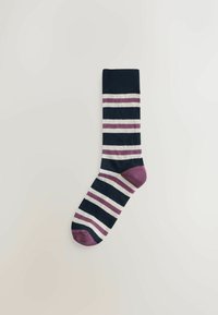 Ein einzelner marineblauer Socke mit horizontalen weißen und lila Streifen sowie einer einfarbigen lila Fußspitze und Ferse auf einem hellen Hintergrund.