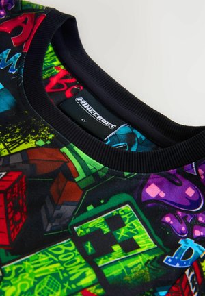Kindershirt met Minecraft-thema met kleurrijke gepixelde ontwerpen en een zwarte geribbelde kraag, maatlabel met 6 jaar.