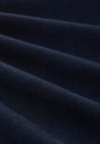 Tissu bleu marine foncé avec une texture douce et lisse, drapé en plis horizontaux réguliers créant des ombres douces.