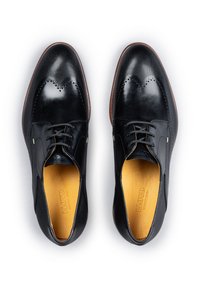 Zwarte leren schoenen met een gestructureerd patroon en brogue-details. Veters en een tan interieur accentueren het ontwerp. Slank, afgerond model.