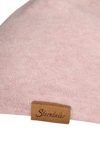 Soft pink textured fabric with a small brown leather tag embossed with the word "Sterntaler."