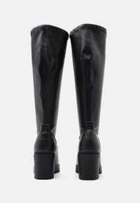 Fekete, térd fölé érő csizmák sima bőrből, lekerekített orral, tömbsarokkal és varrott részletekkel az érésnél és a hátsó fülön.