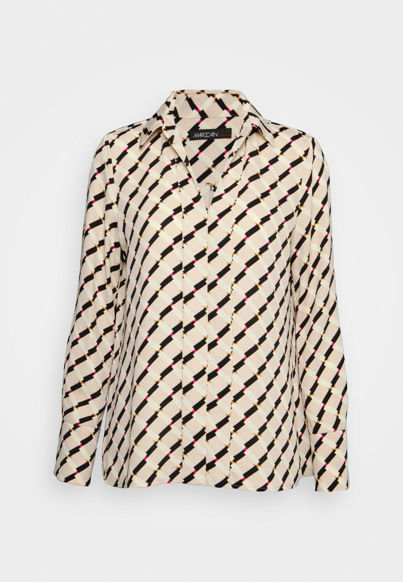 Blouse crème à manches longues avec motif géométrique diagonal noir, beige et rose et col classique.
