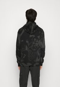 Hoodie noir avec un grand imprimé graphique dans le dos, mettant en scène un joueur de basketball. Fabriqué en tissu doux, avec une capuche à cordon de serrage et des motifs complexes.
