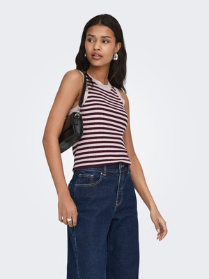 Young woman wearing a sleeveless striped top, dark blue jeans, silver hoop earrings, carrying a small black shoulder bag, looking to the side.