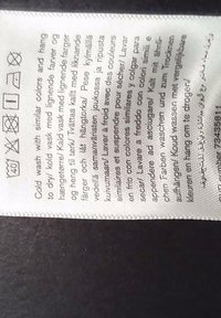 Mosási címke szimbólumokkal és utasításokkal hideg mosáshoz, vasaláshoz, fehérítőszer nélkül, szárítógép használata nélkül, és hasonló színű ruhák légszárításához.