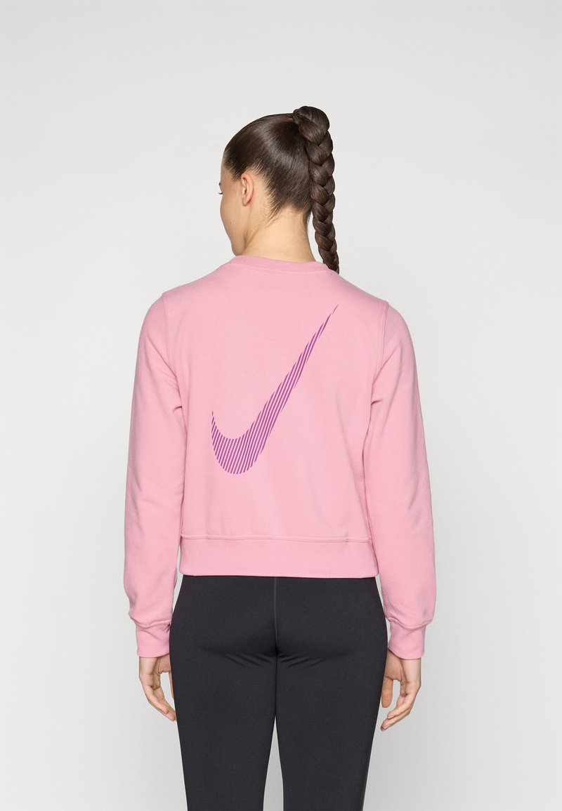 Sweatshirt rose avec une texture côtelée, présentant un grand logo Nike à rayures violettes au dos. Design court et manches longues.