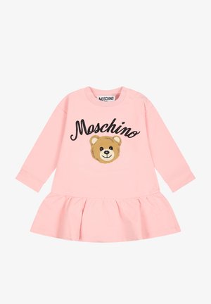 Lyserød babykjole med lange ærmer og flæsekant, med teksten "Moschino" og et smilende bamseansigt på fronten.