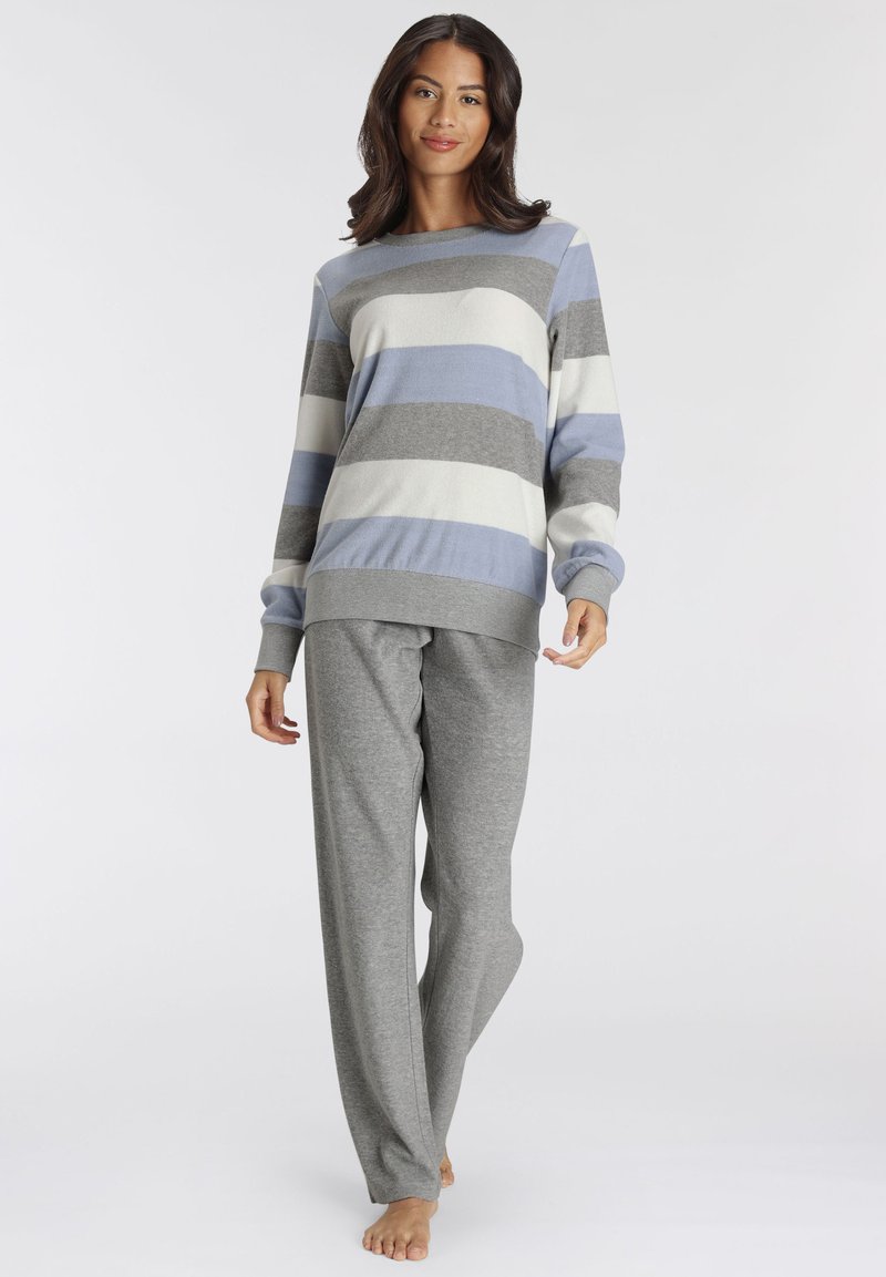 Striped sweater in light blue, gray, and white, paired with gray lounge pants. Soft texture, loose design, and crew neckline.