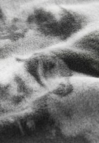 Pelēka un balta auduma ar maigu tekstūru, ar izplūdušiem rakstiem un vieglu gradientu, radot slāņainu izskatu.