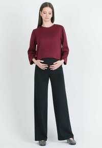 Burgundy cropped sweater with long sleeves, paired with high-waisted black wide-leg trousers and black studded flat shoes.
