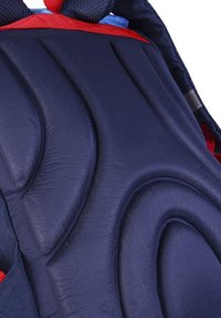 Navy blue padded backpack with contoured design, featuring raised textured patterns and red accents. Polyester material, ergonomic shape.