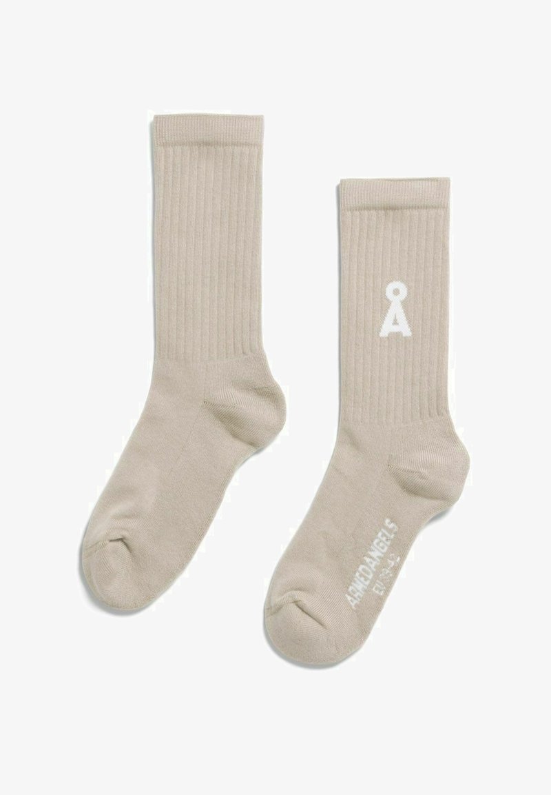 Chaussettes beige côtelées montant jusqu'à la cheville avec un logo blanc "Å" sur une chaussette et le texte "Amiø Angels" sur la semelle de l'autre chaussette.