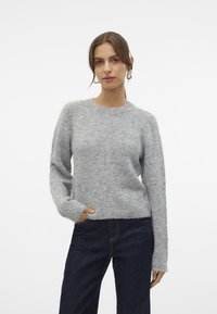 Gray knit sweater with a round neckline, long sleeves, and a relaxed fit. Soft texture, worn over dark denim jeans. Simple and classic design.