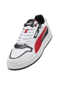 Sneaker bianco con dettagli neri e rossi, realizzato in pelle sintetica. Presenta un logo Puma prominente, design con lacci e suola testurizzata.
