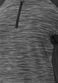 Grå träningsskjorta med dragkedja vid kragen, med ett texturerat, linjärt mönster och kontrasterande svarta detaljer på ärmarna. Mjuk och andningsbar fabric.