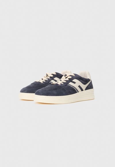 Pair of navy suede sneakers with white rubber soles and beige laces, featuring a white side stripe and padded ankle collars.