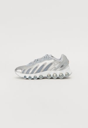 Baskets de sport argentées et grises avec des parties en mesh, des coussins d'air visibles le long de la semelle blanche, et un petit logo Nike swoosh.